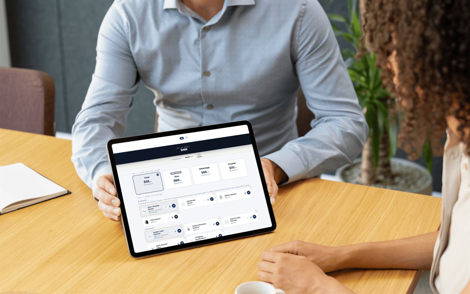 Building an alarm quote on a tablet at the kitchen table — monitoring plans and equipment with live out-of-pocket pricing